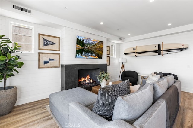 living area featuring wood finished floors, visible vents, recessed lighting, and a high end fireplace