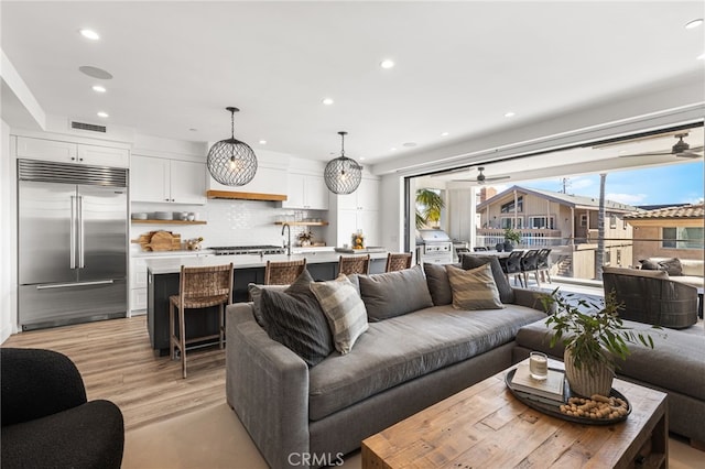 living area with ceiling fan, light wood-type flooring, visible vents, and recessed lighting