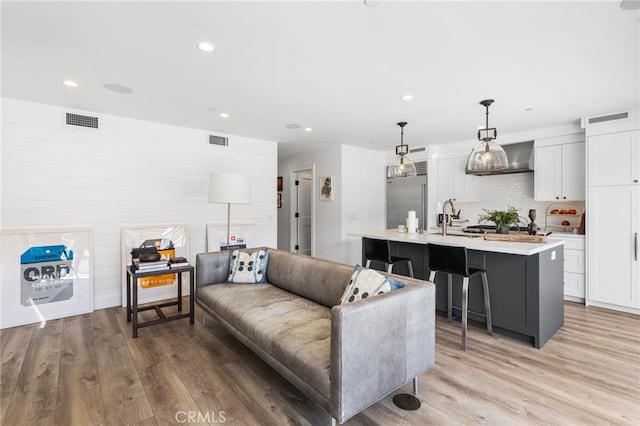 living room with recessed lighting, light wood-type flooring, and visible vents