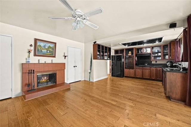 13771 De Garmo Ave, Rancho Cascades, CA 91342 - unfurnished living room featuring light wood finished floors, a tile fireplace, ceiling fan, a sink, and baseboards