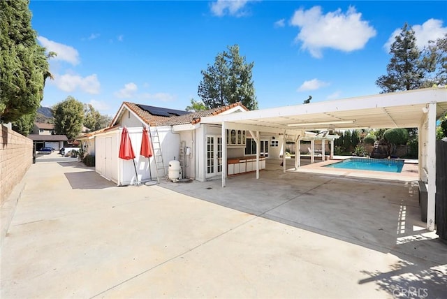13771 De Garmo Ave, Rancho Cascades, CA 91342 - rear view of house with roof mounted solar panels, a patio area, an outdoor pool, a tile roof, and a fenced backyard