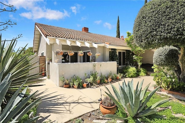 13771 De Garmo Ave, Rancho Cascades, CA 91342 - back of house featuring a tiled roof, a chimney, stucco siding, and fence