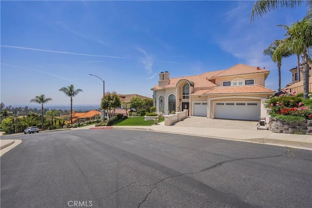 8113 Newcastle Dr, Whittier, CA 90605 - mediterranean / spanish house with driveway, a chimney, a tiled roof, an attached garage, and stucco siding
