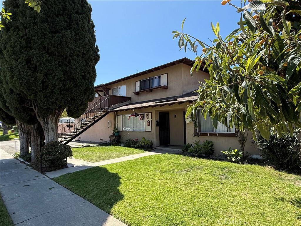 2602 W Aurora St Unit 4, Santa Ana, CA 92704 - view of front of home featuring stucco siding, stairway, and a front lawn