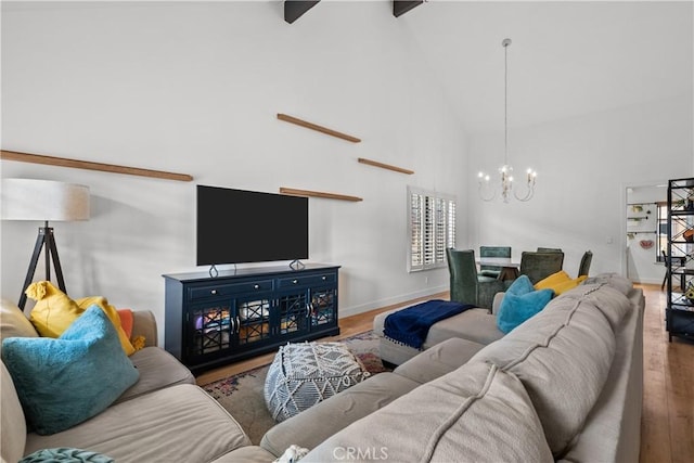 living area with a chandelier, wood finished floors, high vaulted ceiling, and baseboards
