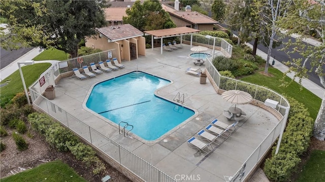 pool with a patio, fence, and a hot tub