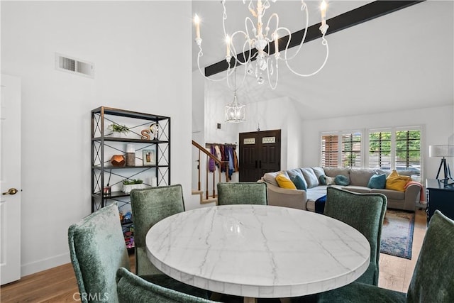 dining room with baseboards, an inviting chandelier, stairway, visible vents, and wood finished floors