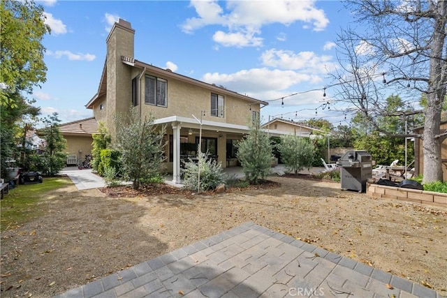 rear view of property with a patio, stucco siding, and a chimney