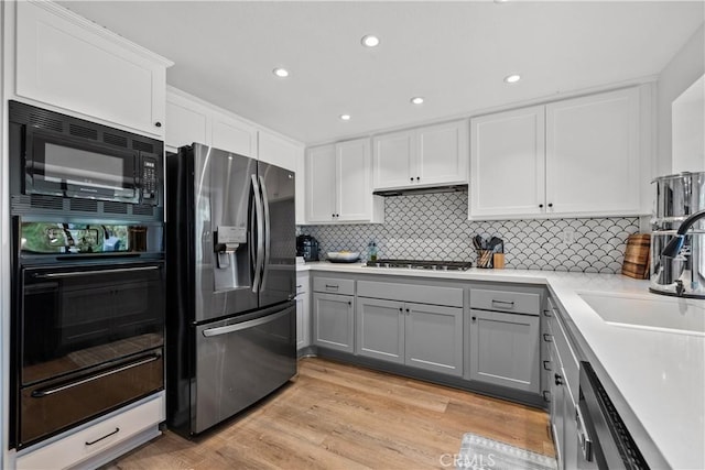kitchen with black appliances, light countertops, a sink, gray cabinetry, and backsplash