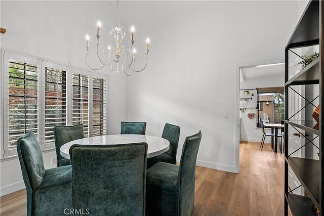 dining space with wood finished floors, an inviting chandelier, and baseboards