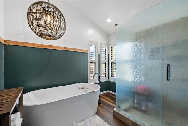 bathroom with a shower stall, a freestanding bath, wood finished floors, and vaulted ceiling