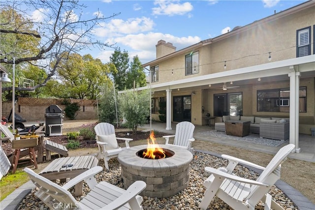 back of property with a patio area, an outdoor living space with a fire pit, a chimney, fence, and stucco siding
