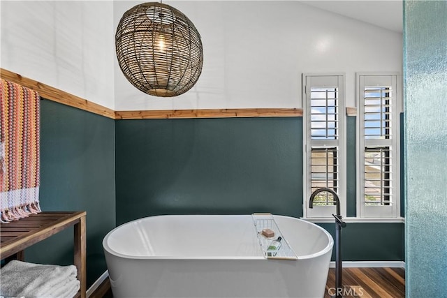 full bath with baseboards, a freestanding tub, and wood finished floors