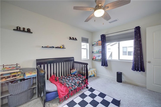 carpeted bedroom with visible vents, baseboards, and a ceiling fan
