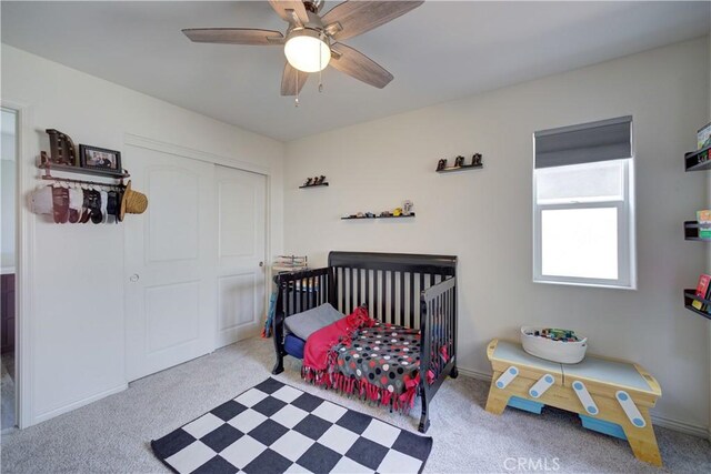 carpeted bedroom featuring a closet, baseboards, and a ceiling fan