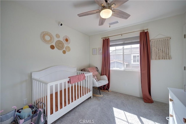 bedroom with carpet flooring, visible vents, a nursery area, and ceiling fan