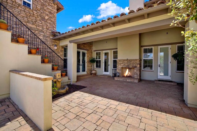 view of patio / terrace with stairway, an outdoor stone fireplace, and french doors