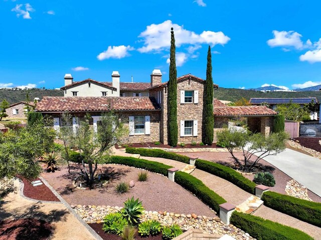mediterranean / spanish home with a chimney, a tile roof, a mountain view, and stone siding