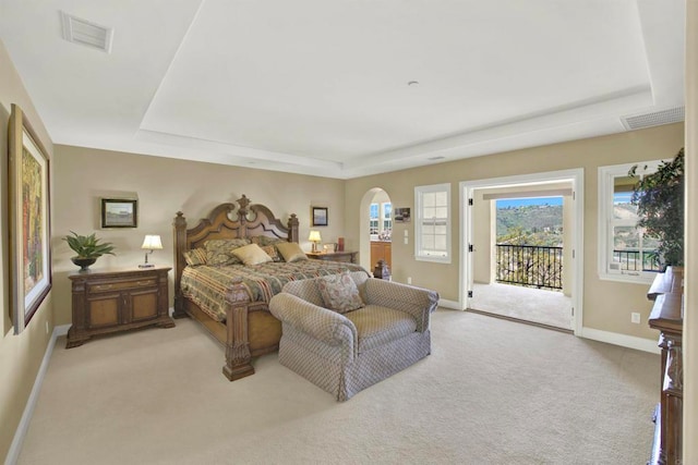 bedroom with visible vents, arched walkways, a raised ceiling, and access to exterior