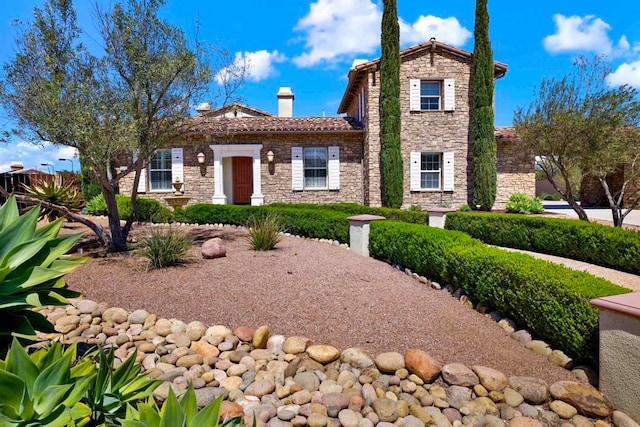 mediterranean / spanish-style house featuring stone siding and a chimney