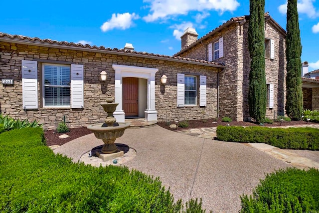 view of front of property with stone siding and a chimney