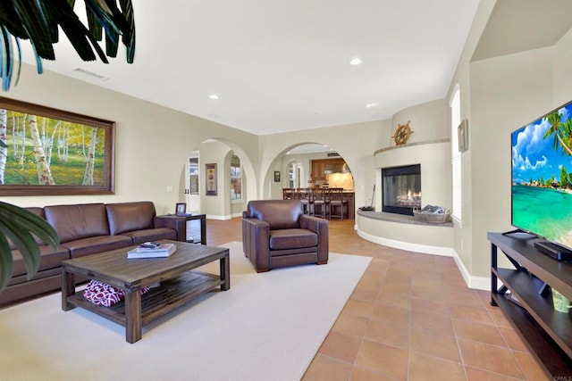 tiled living area with arched walkways, visible vents, baseboards, and recessed lighting