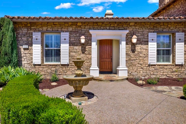 view of exterior entry featuring a chimney and stone siding
