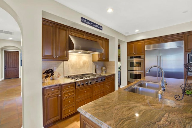 kitchen featuring ventilation hood, visible vents, a sink, arched walkways, and appliances with stainless steel finishes