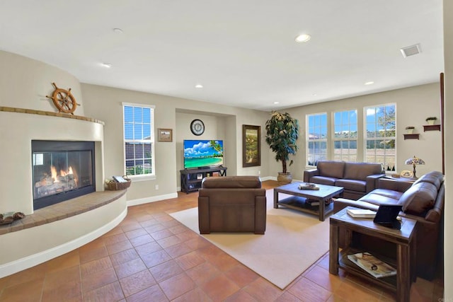 living room featuring a glass covered fireplace, baseboards, visible vents, and recessed lighting