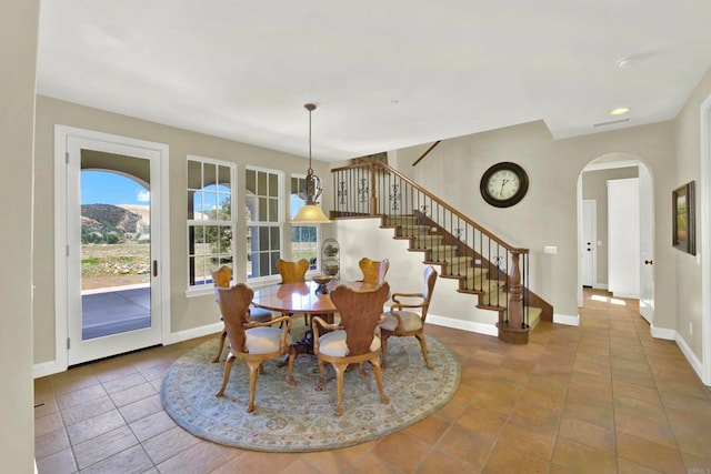 dining room with arched walkways, stairway, tile patterned flooring, and baseboards