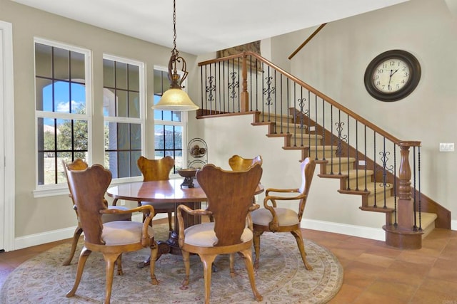 tiled dining space featuring baseboards and stairs