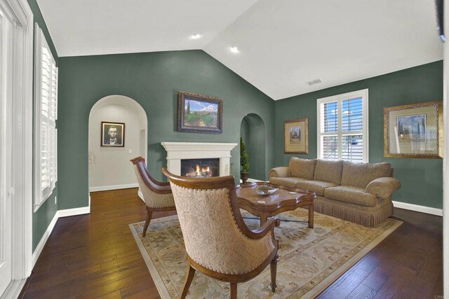 11443 Stockwood Cv, San Diego, CA 92131 - living area featuring arched walkways, lofted ceiling, a glass covered fireplace, and hardwood / wood-style flooring