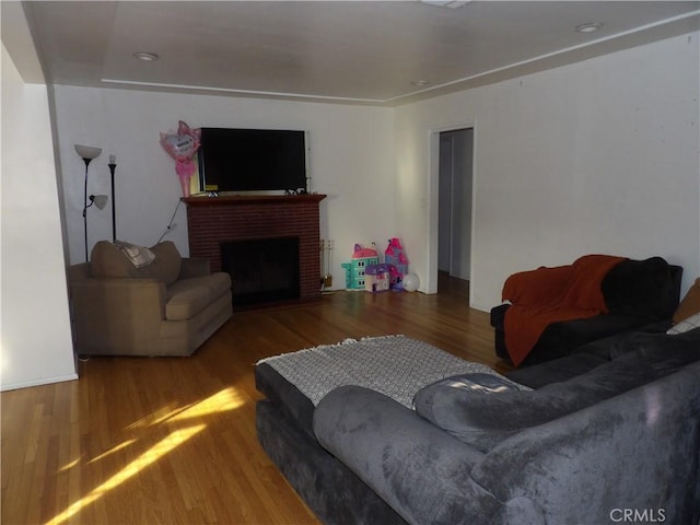 living area with a brick fireplace and wood finished floors