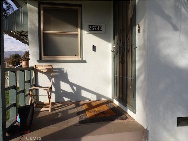 entrance to property with covered porch and stucco siding