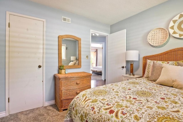 bedroom featuring visible vents, carpet, and a textured ceiling