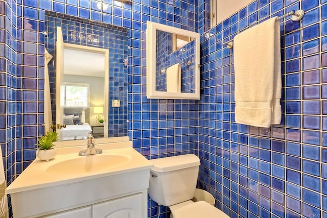 ensuite bathroom with toilet, vanity, ensuite bath, and tile walls