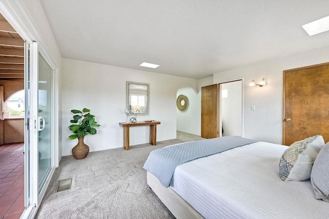 bedroom with light carpet, arched walkways, visible vents, and multiple windows
