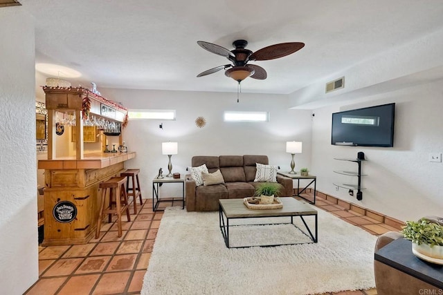 living area featuring tile patterned floors, a dry bar, a ceiling fan, and visible vents