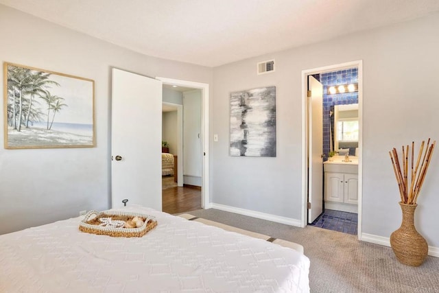 bedroom with light carpet, baseboards, visible vents, and connected bathroom