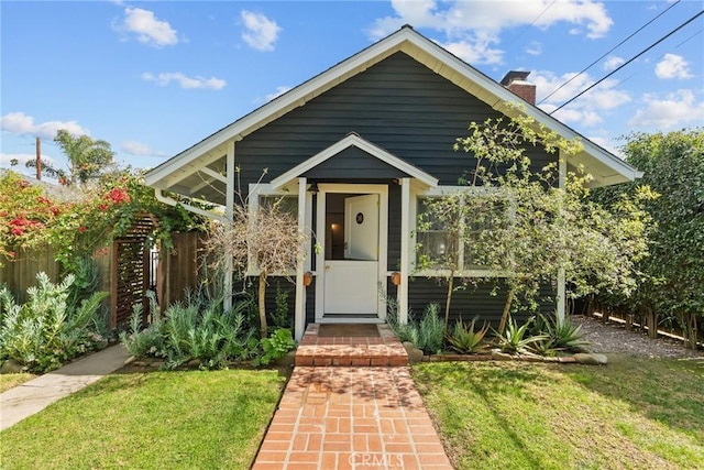 view of front facade with a front yard, fence, and a chimney