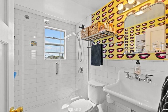 bathroom with tile walls, a sink, a stall shower, and toilet