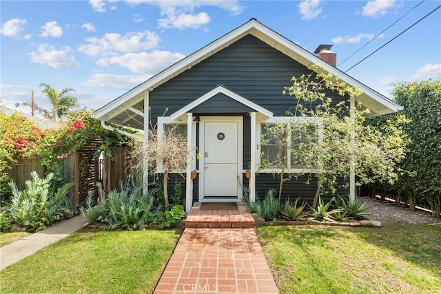 view of front of home with a front lawn, a chimney, and fence