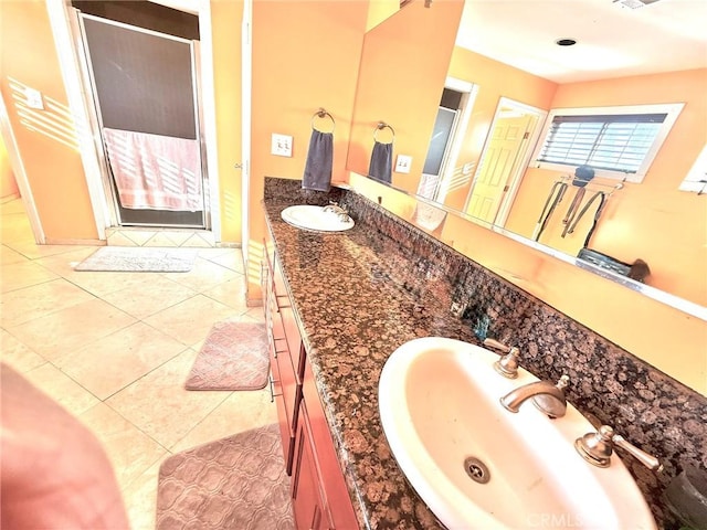 full bathroom with double vanity, a sink, tile patterned floors, and a stall shower