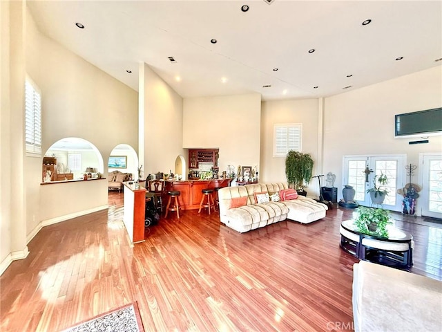 living room featuring visible vents, baseboards, a towering ceiling, recessed lighting, and light wood-type flooring