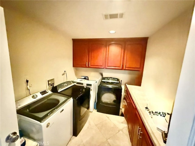 clothes washing area featuring light tile patterned flooring, cabinet space, visible vents, and washer and dryer