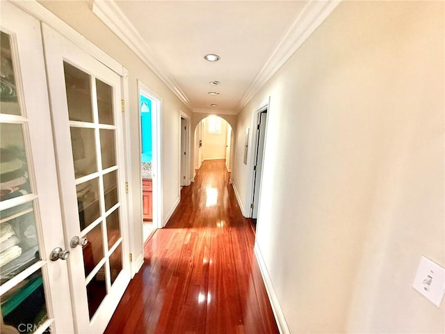 hall featuring crown molding, french doors, dark wood-style flooring, baseboards, and arched walkways