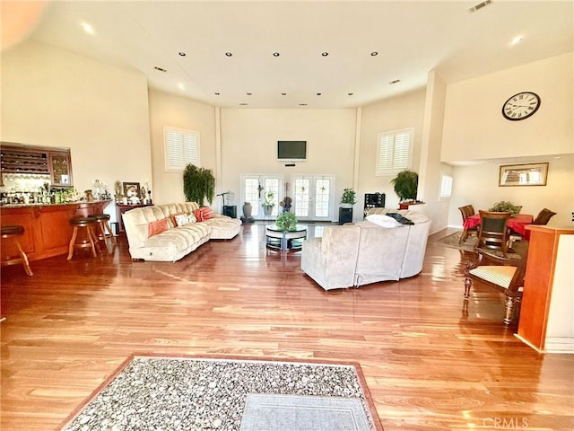 living area featuring light wood-type flooring, a towering ceiling, and recessed lighting