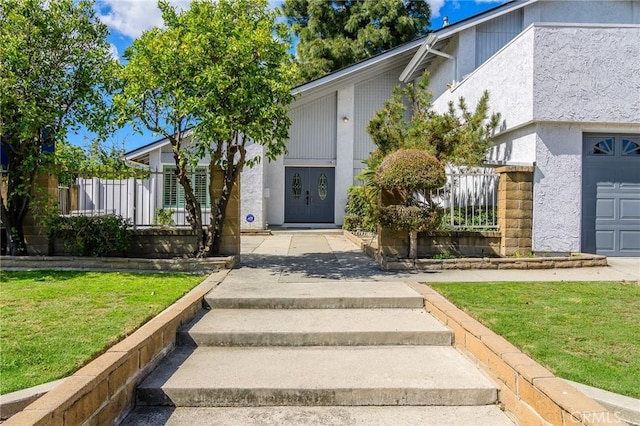 doorway to property featuring a lawn and stucco siding