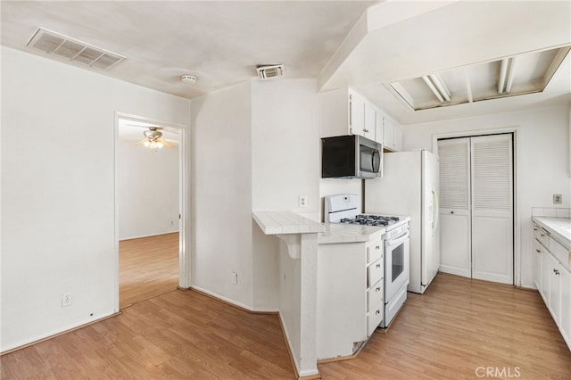 1 Brandy Ln Unit 23, Aliso Viejo, CA 92656 - kitchen featuring white gas stove, stainless steel microwave, tile counters, and white cabinets