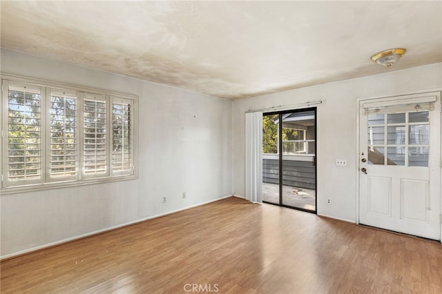 spare room with baseboards and wood finished floors